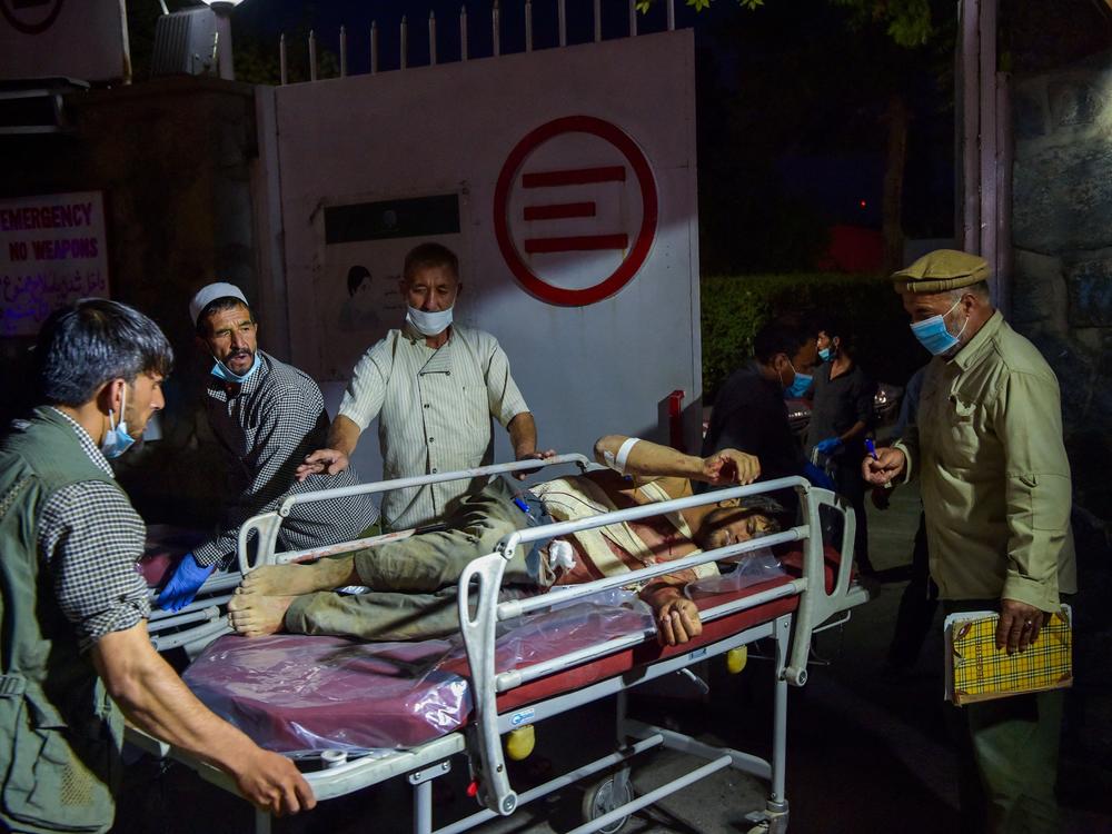 <strong>Thurs., Aug. 26: </strong>Medical and hospital staff bring an injured man for treatment after two powerful explosions outside the airport in Kabul.