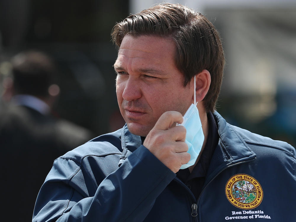 Florida Gov. Ron DeSantis takes his mask off as he prepares to speak during a press conference at the Hard Rock Stadium testing site in Miami Gardens, Fla., in May 2020.