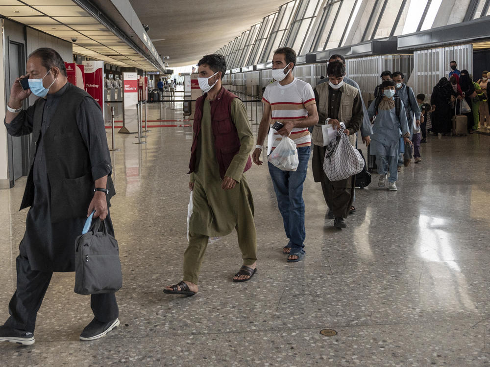 Refugees from Afghanistan are escorted to a bus after arriving and being processed Monday at Dulles International Airport in Virginia. The federal government is reportedly offering COVID-19 vaccines for Afghan arrivals at a site near the airport.