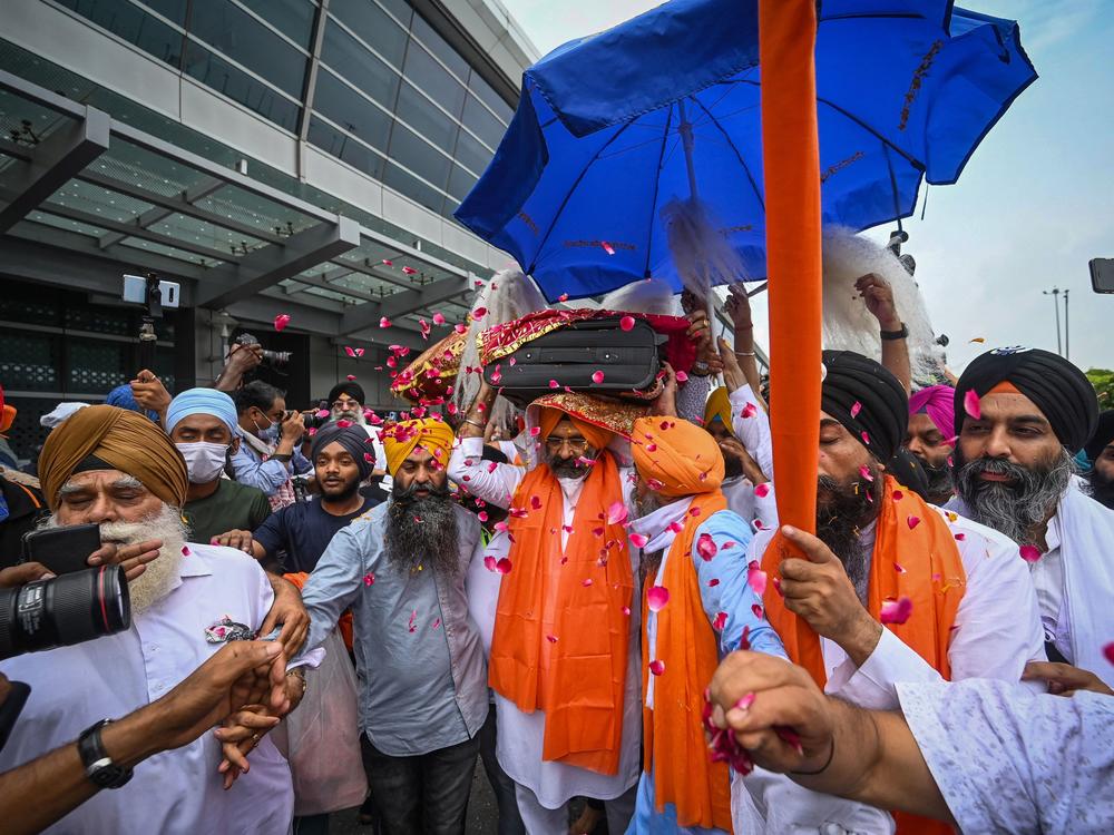 A man carries the Guru Granth Sahib, the Sikh holy book, brought to India by Afghan Sikhs who were evacuated and landed at the Indira Gandhi International Airport in New Delhi on Aug. 24.