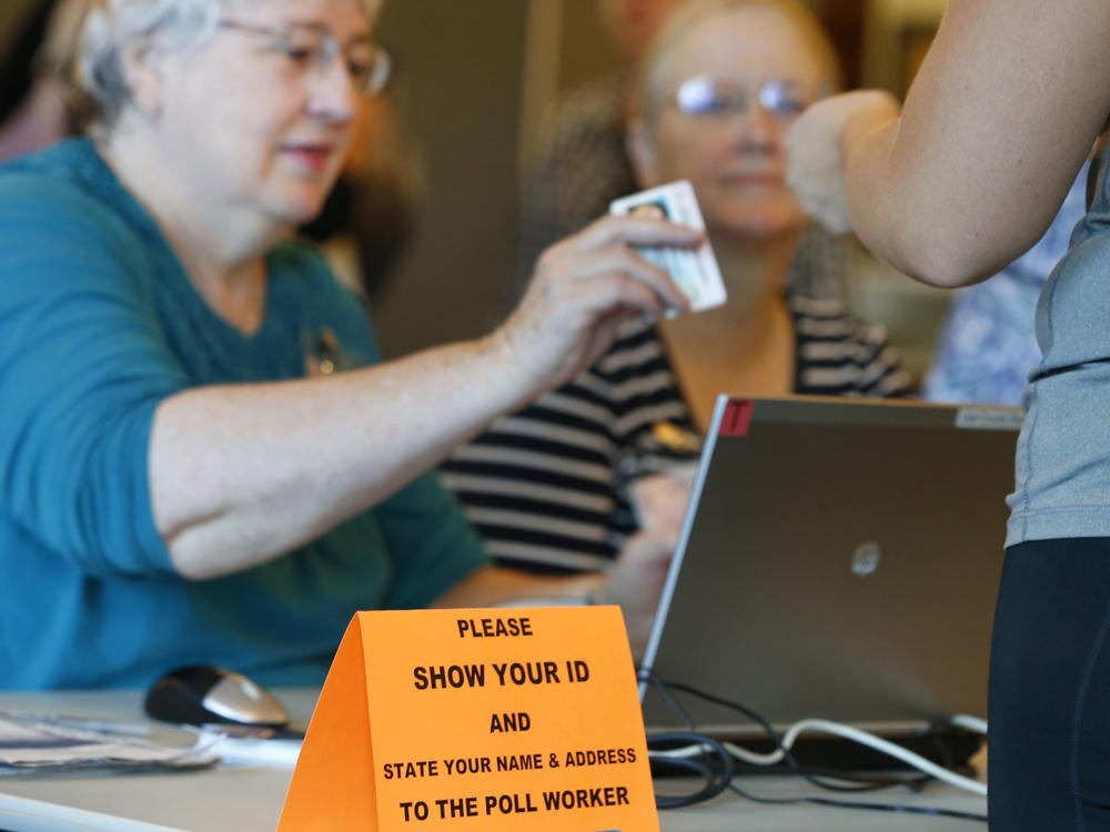 A Utah poll worker checks a voter ID during the 2016 presidential election. Eleven states have strict voter ID laws, while 24 have less stringent laws for an ID to vote. Democrats have begun to lower their resistance to the issue.
