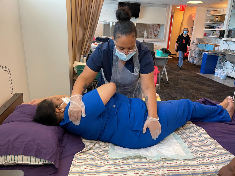 Juhaley Abrau, a student at Cooperative Home Care Associates, practises how to safely give her fellow student, Tashawna Vivas, a bedbath. Abrau says a lot of the programs she looked at were all 