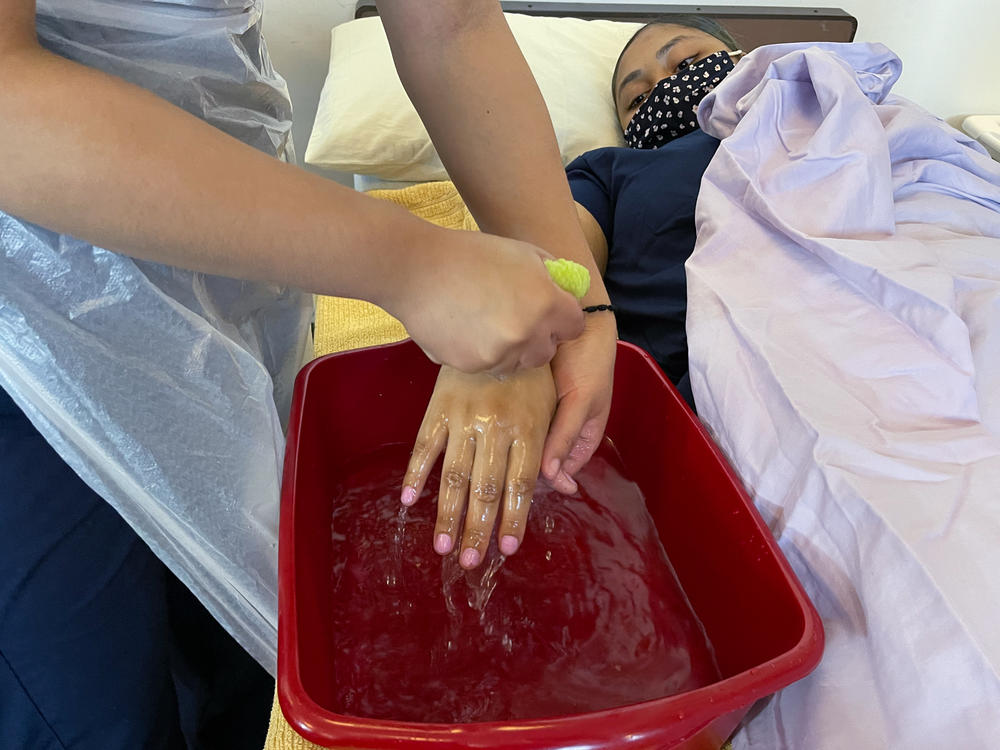 Students at a training program, Cooperative Home Care Associates in New York, practice basic skills like a bed-bath on each other. Home health aides, provide basic, day-to-day support for elderly and disabled people, allowing them to age at home.