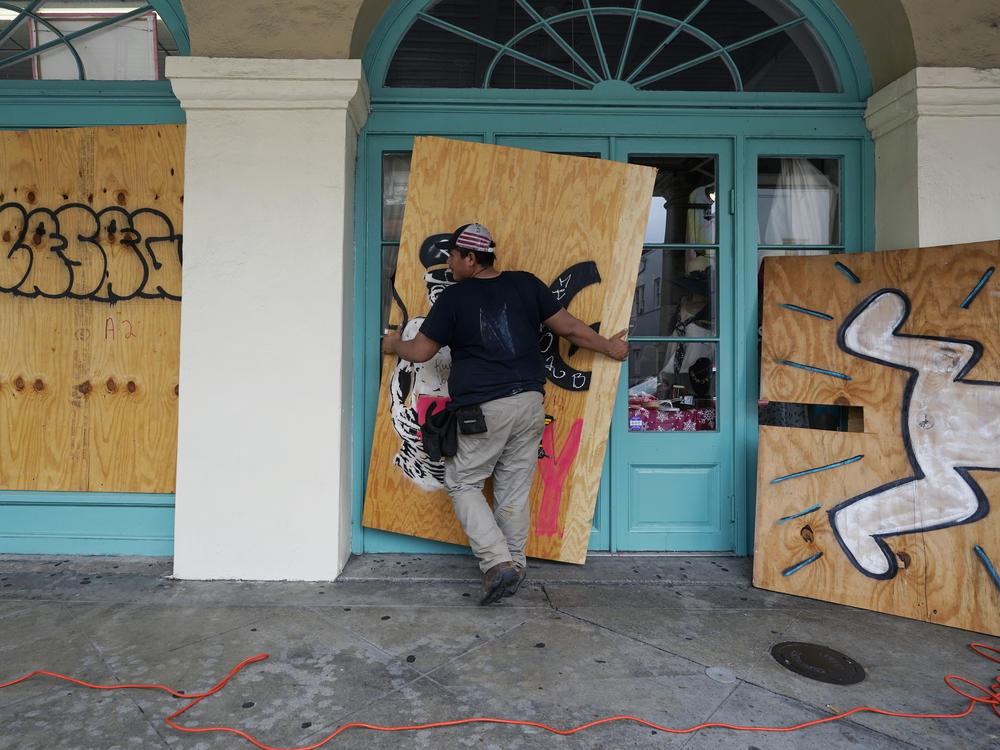 In preparation of Hurricane Ida, a workers attach protective plywood to windows and doors of a business in the French Quarter in New Orleans on Saturday.