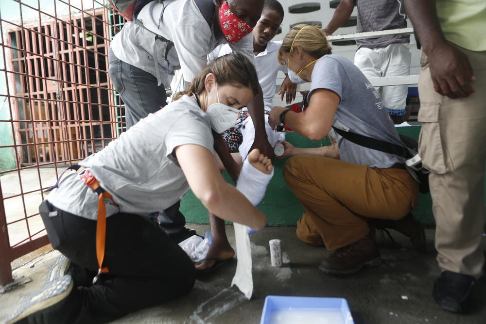 Drs. Maddie Ross and Heidi Haavik of Team Rubicon wrap a cast for Kendy Cazeau, 14, who sustained a broken leg in the earthquake.