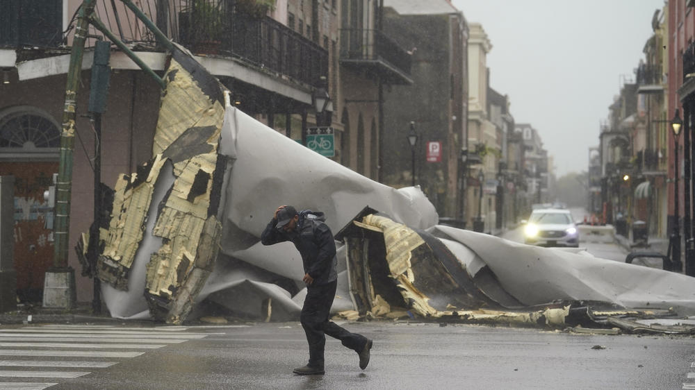 A man passes by a section of roof that was blown off of a building in the French Quarter by Hurricane Ida winds on Sunday in New Orleans.