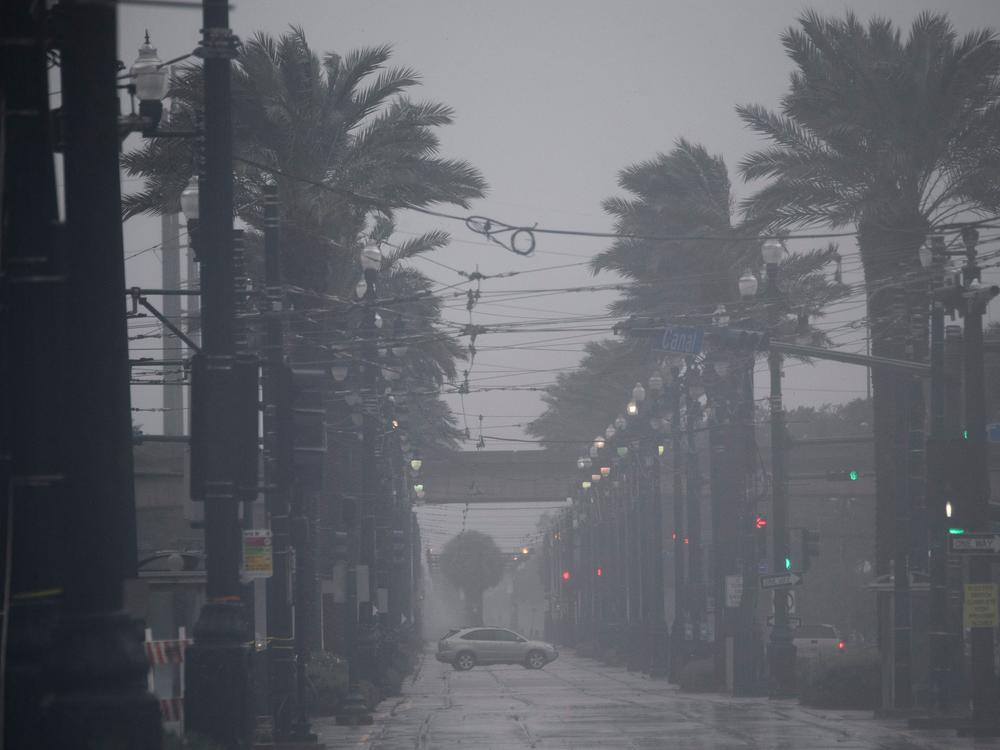 A vehicle drives through rain and high winds across Canal Street in New Orleans on Sunday afternoon.