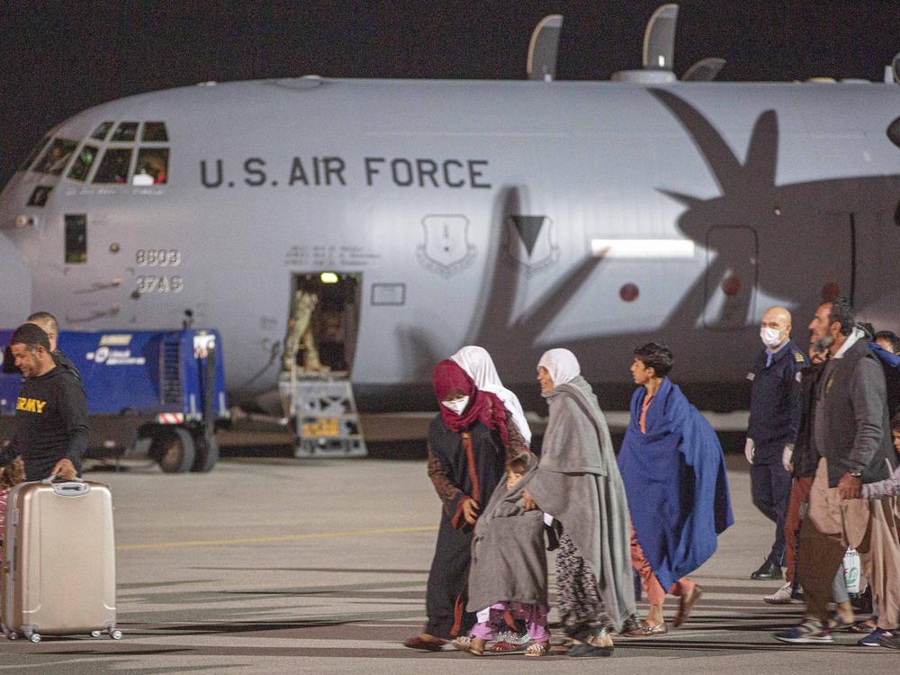 Families evacuated from Kabul, Afghanistan, walks past an U.S air force airplane that flew them at Kosovo's capital Pristina International Airport on Sunday, Aug. 29, 2021.
