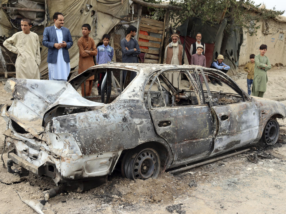 Locals view a vehicle damaged by a rocket attack in Kabul, Afghanistan, Monday, Aug. 30, 2021. Rockets struck a neighborhood near Kabul's international airport on Monday amid the ongoing U.S. withdrawal from Afghanistan. It wasn't immediately clear who launched them.