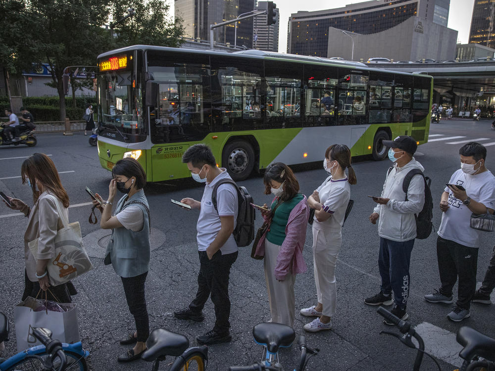 Commuters wait in line for public buses as they leave work in Beijing's business district on Aug. 27. China's Supreme People's Court has ruled that it's illegal for companies to subject employees to the practice known as 