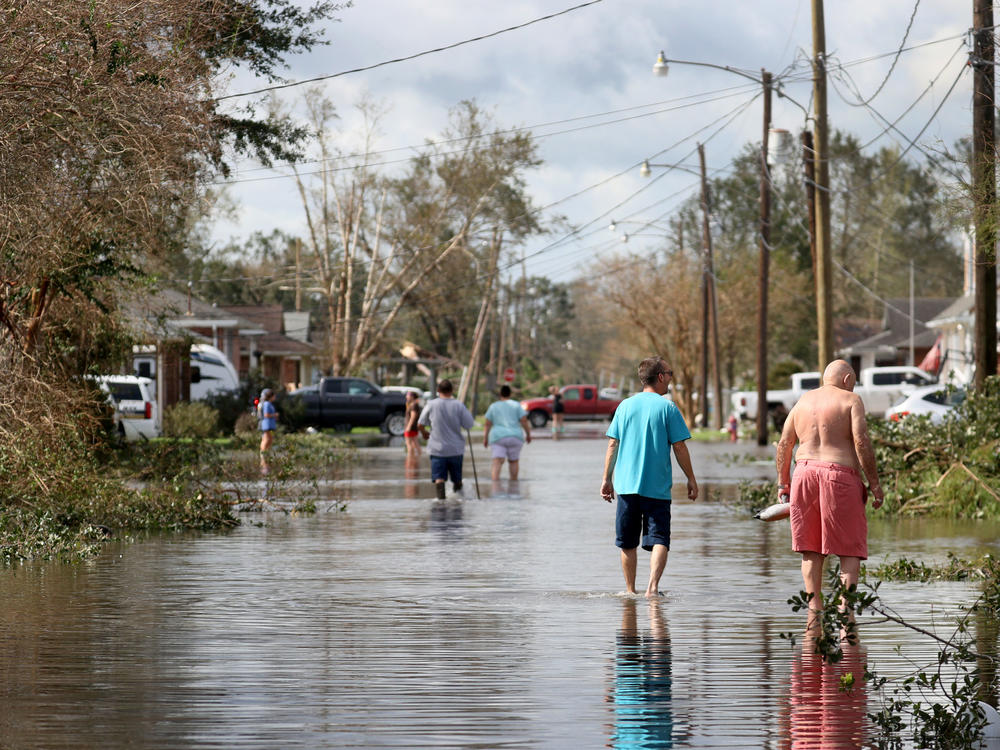 Residents walk down a flooded residential street in the aftermath of Hurricane Ida on Monday in Norco, La. Ida made landfall on Sunday as a Category 4 storm southwest of New Orleans.