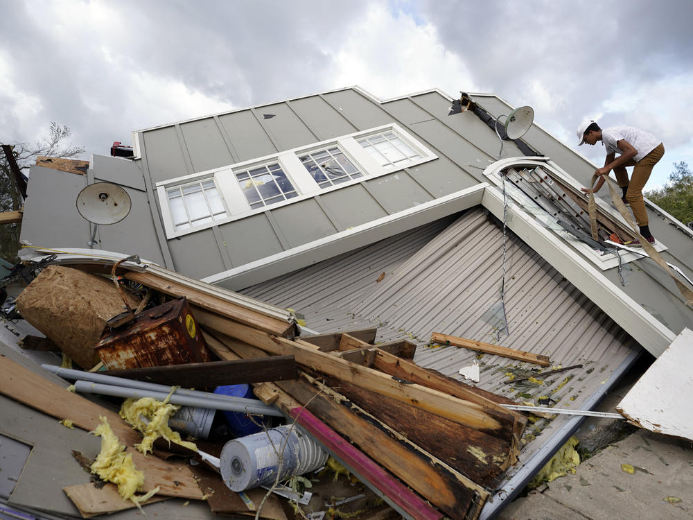 Jeremy Hodges climbs up the side of his family's destroyed storage unit on Monday, in Houma, La., which sits just along the coast of Louisiana.