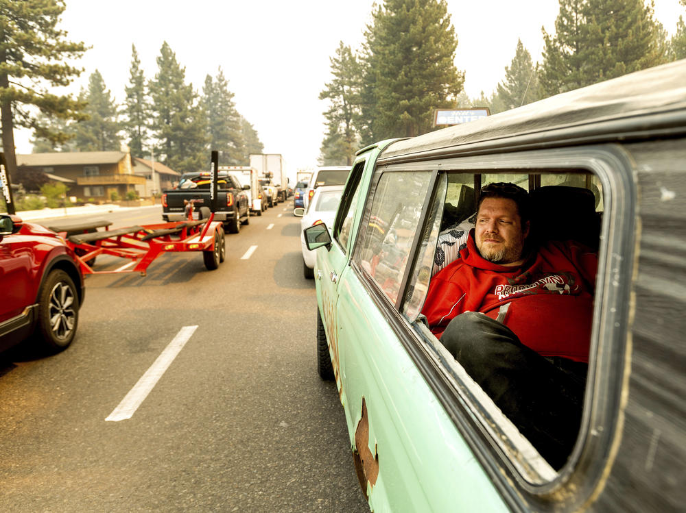 As the Caldor Fire approaches South Lake Tahoe, Calif., 40-year Tahoe resident Chris, who declined to give his last name, lies in a pick-up truck while evacuating on Monday, Aug. 30, 2021. His car moved about 60 feet in an hour as evacuating residents filled Highway 50.