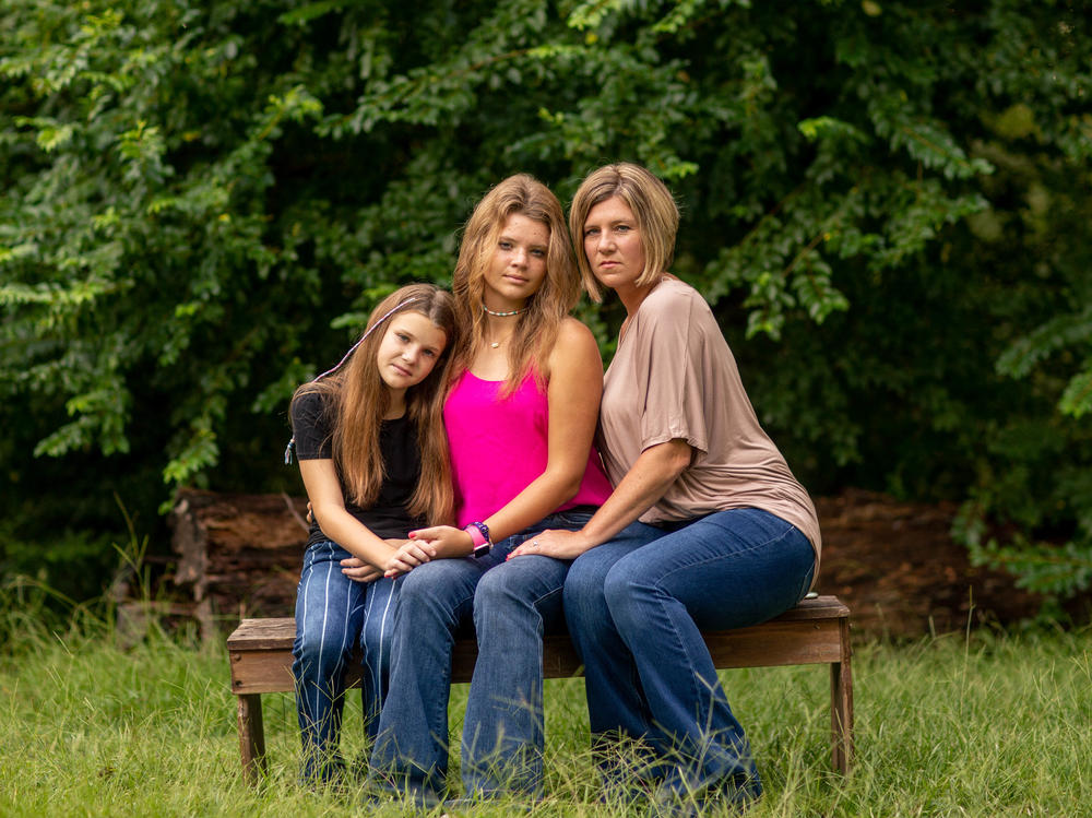 Allie Henderson with her sister Claire (left) and her mom, LeAnn, outside their home recently in Terry, Miss. 