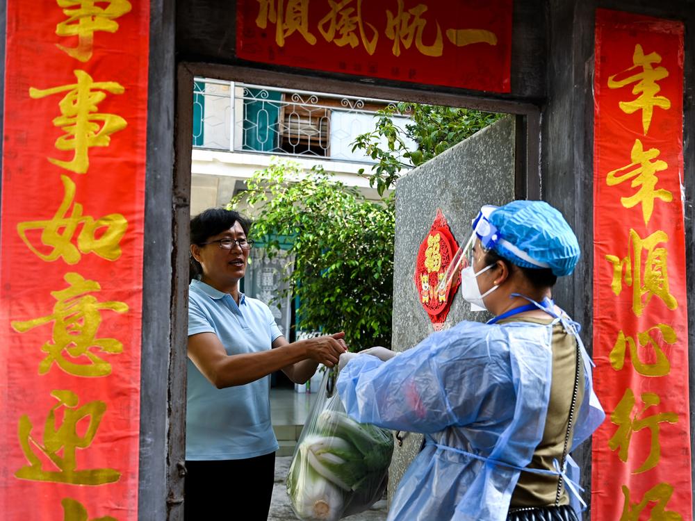 A community worker delivered daily necessities to a household in Ruili City in China's Yunnan Province during a July lockdown triggered by COVID cases. Ruili closed off its city proper and asked all residents to quarantine at home. Classes were suspended. Most establishments were closed with the exception of markets, hospitals and pharmacies. Restaurants could only offer takeout food.