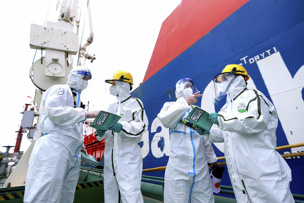 Police officers (left and second from right) wear protective gear as they explain how to fight the spread of Covid-19 to workers at Nanjing port in China's eastern Jiangsu province on August 4.