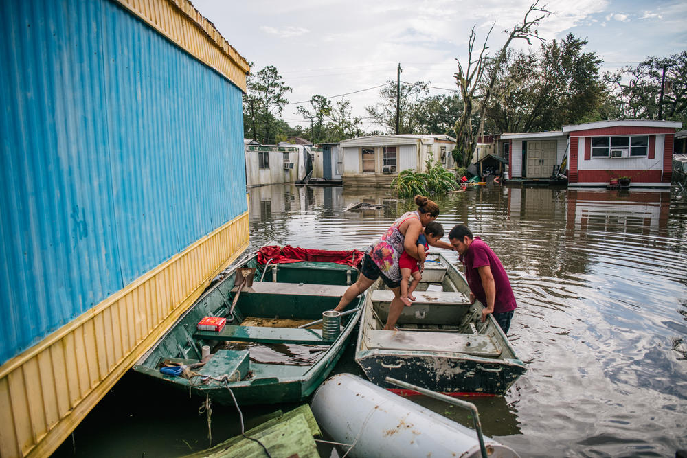Marlon Maldonado helps his wife and child into a boat on Aug. 31 in Barataria, La., to travel to their home after it flooded during Hurricane Ida.