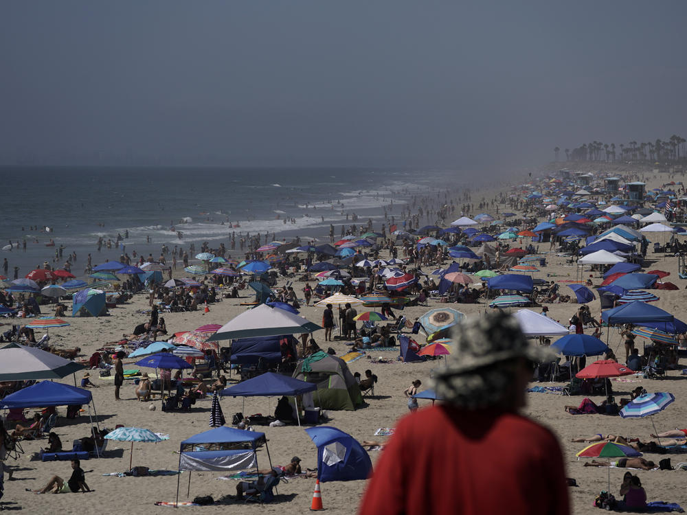 People crowd the beach in Huntington Beach, Calif., over the long Labor Day weekend last year, months before COVID-19 vaccines were available. This year, the CDC is recommending that people who are not fully vaccinated stay home.