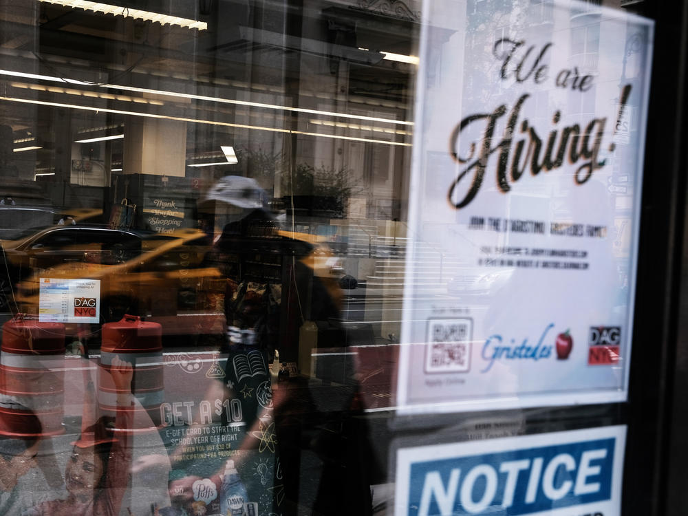 A hiring sign gets displayed in a store window in New York City in August. Last month saw a sharp slowdown in hiring from previous months as the pandemic wears on and creates uncertainty.