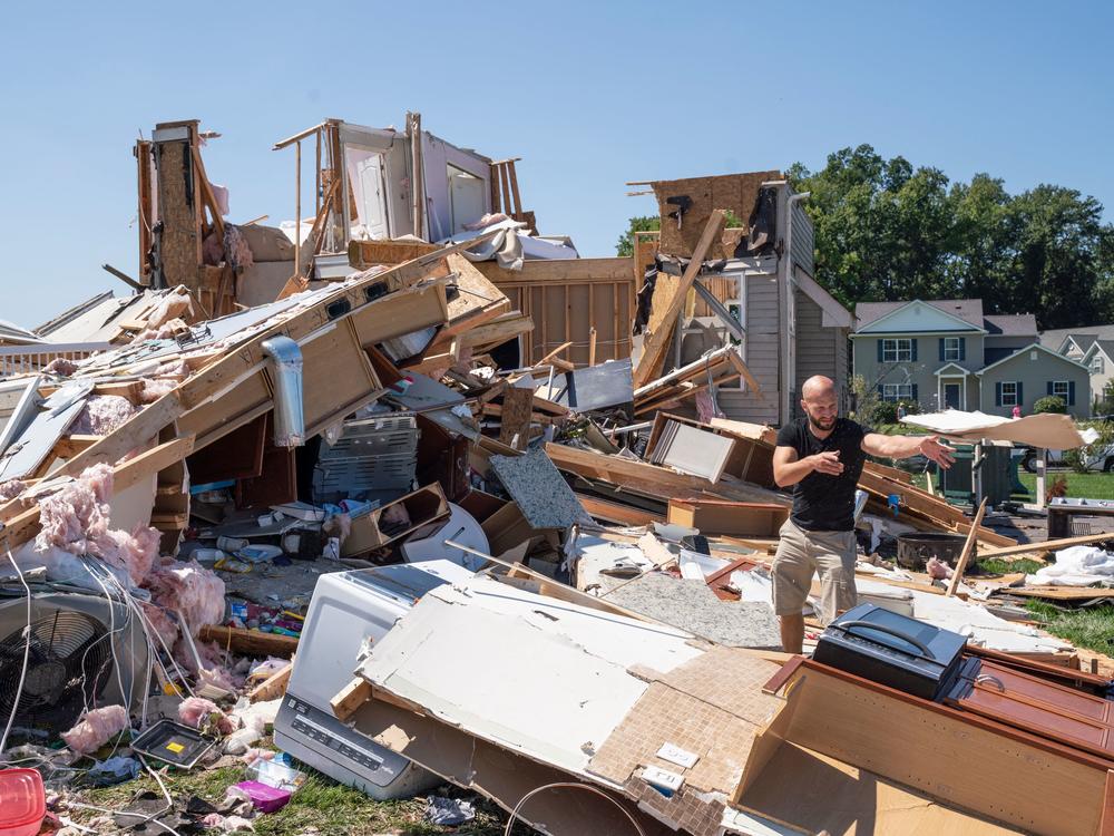 Sam Catrambone clears debris away from a friend's home that was damaged by a tornado in Mullica Hill, N.J., on Thursday after record-breaking rainfall brought by the remnants of Hurricane Ida that swept through the area.
