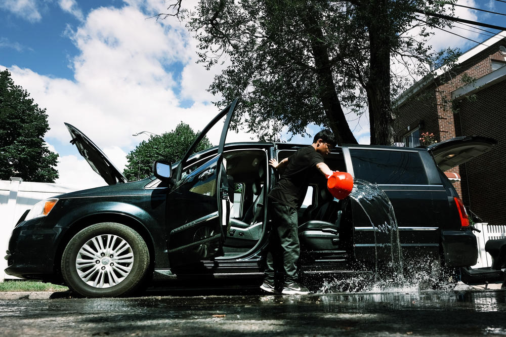 A teenager dumps out water from a car in a flooded Queens neighborhood on Friday. Across the Northeast, people are cleaning up from Ira's wrath.