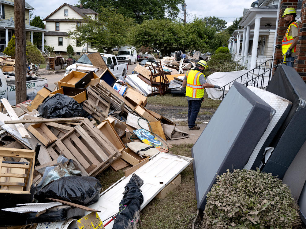 Utility workers work among debris from flood damage caused by the remnants of Hurricane Ida in Manville, N.J., Sunday, Sept. 5, 2021.