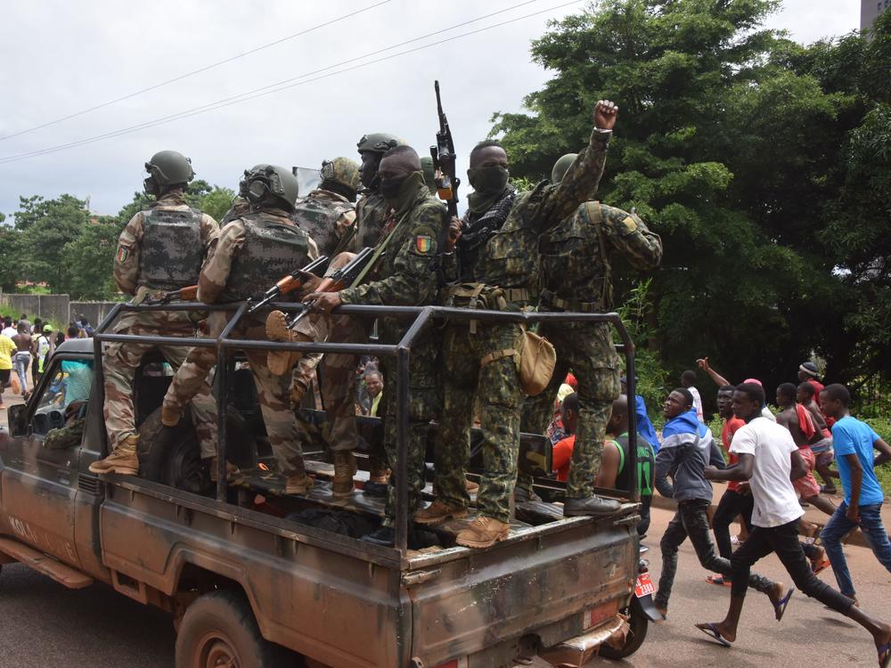 People celebrate in the streets with members of Guinea's armed forces after the arrest of Guinea's president, Alpha Conde, in a coup d'etat in Conakry on Sunday.