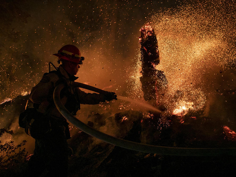 Jason Marone cools down a hot spot burning close to homes last week in the Christmas Valley area of Meyers, Calif.