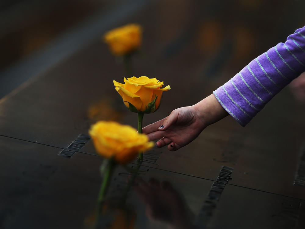 A child reaches out to touch a flower adorning the Sept. 11 memorial on the name of a veteran killed in the 2001 terror attacks. For today's generation of kids, 9/11 is a history lesson.