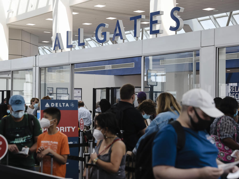 Travelers wearing protective face masks wait in line at a Transportation Security Administration screening at LaGuardia Airport in New York last month. U.S. aviation regulators are calling on the nation's airports to crack down on the defiantly unmasked.