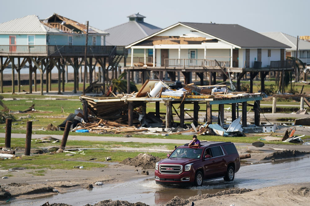On Sept. 3, a motorist drives past houses damaged by Hurricane Ida in Grand Isle, La. Ida made landfall as a Category 4 hurricane, causing flooding, wind damage and power outages along the Gulf Coast.