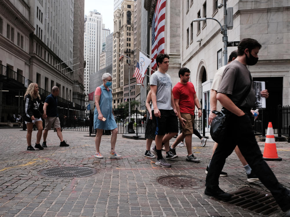 People walk by the New York Stock Exchange (NYSE) on Aug. 10 in Lower Manhattan. Residential buildings have injected new life to a district that would become largely deserted in the evenings.