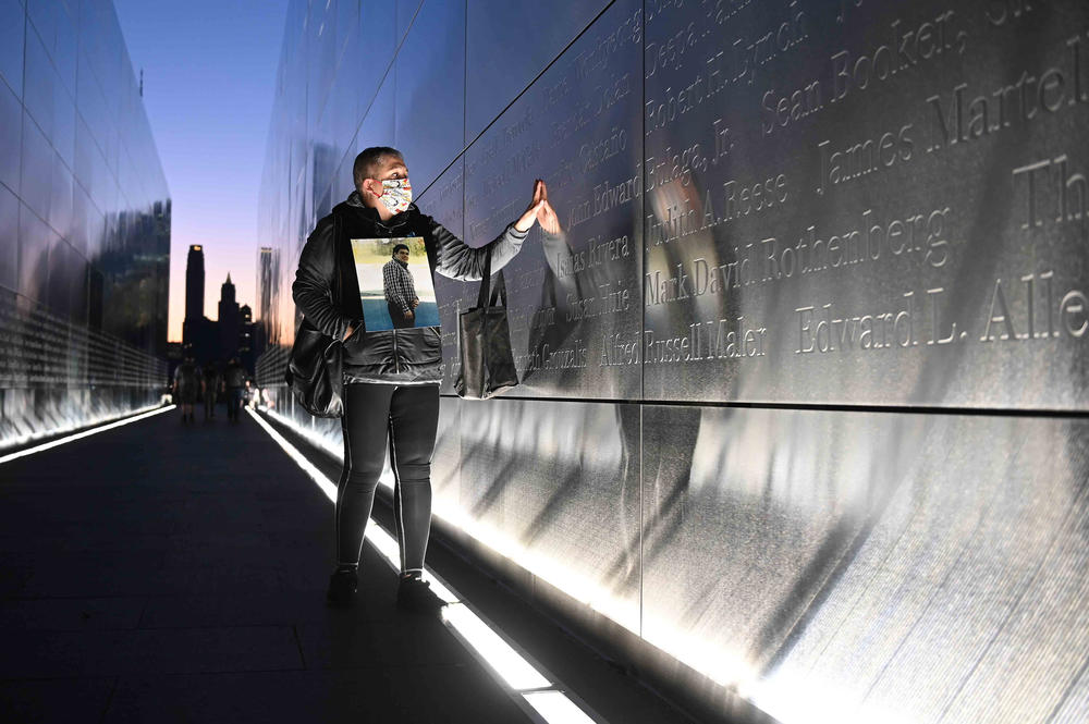 Claudia Castano touches the name of her brother that is etched at the Empty Sky 9/11 Memorial in Liberty State Park in Jersey City, N.J., on Saturday.