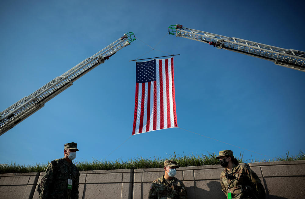 Soldiers wait below an American flag prior to the start of the Pentagon 9/11 observance ceremony at the National 9/11 Pentagon Memorial on Saturday in Arlington, Va.