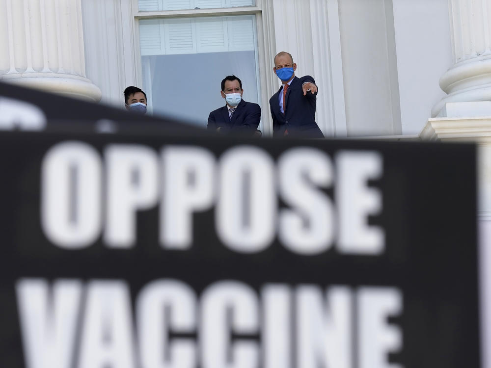 Assembly Speaker Anthony Rendon of Lakewood (center) and Assemblyman Kevin McCarty, D-Sacramento, (right) watch from the balcony outside the Assembly Chambers as protesters opposing vaccine mandates gather at the Capitol in Sacramento, Calif.