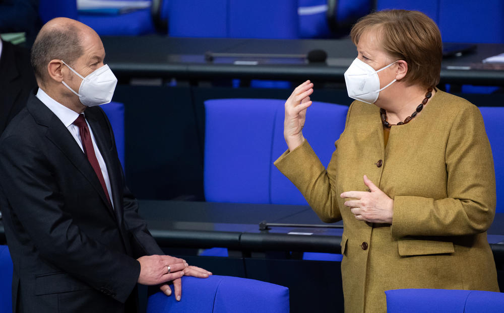 Olaf Scholz, Germany's finance minister, and Chancellor Angela Merkel talk at the beginning of the plenary session in the German parliament, the Bundestag, in Berlin on Jan. 28.