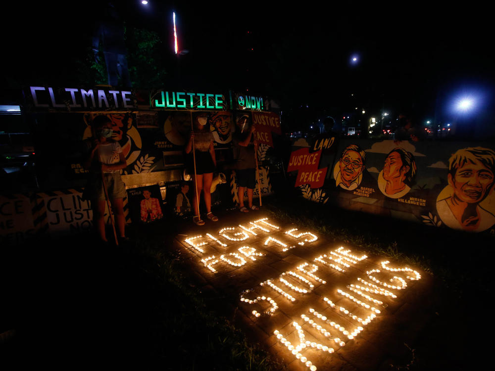 Climate activists in Quezon City, Philippines, light candles and hold LED-illuminated banners in December of last year to commemorates five years since the Paris Agreement and to call for an end to the killing of environmental defenders.