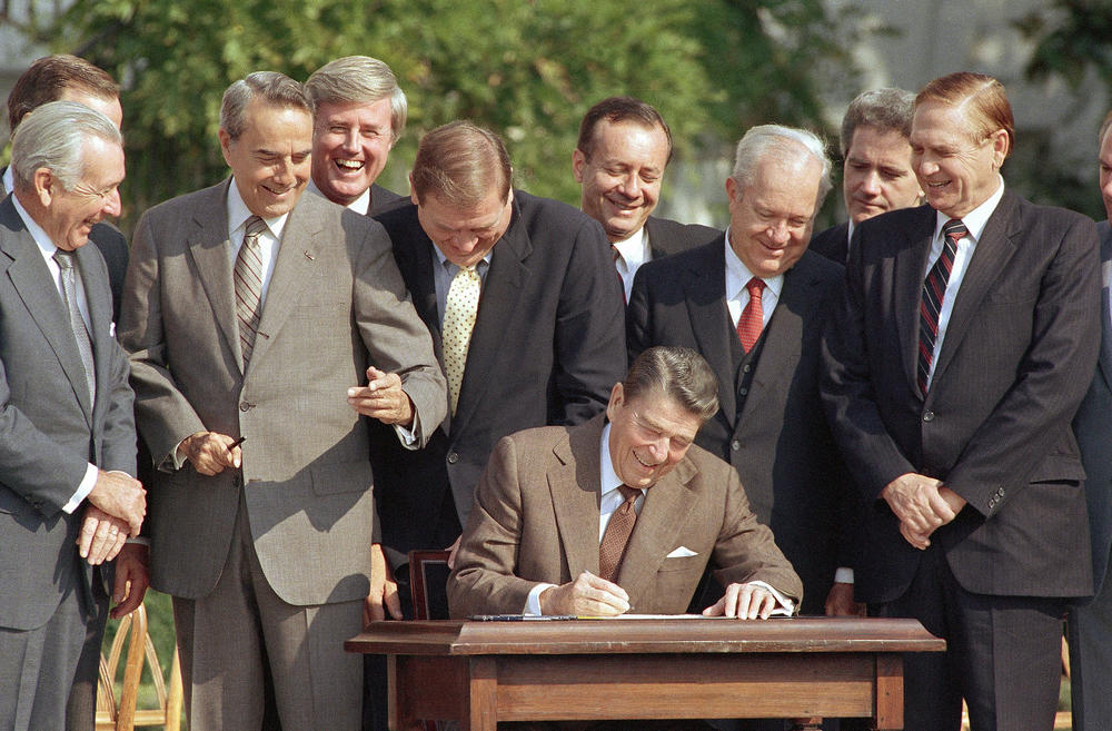 Lawmakers watch as Reagan signs into law a landmark tax overhaul in October 1986.