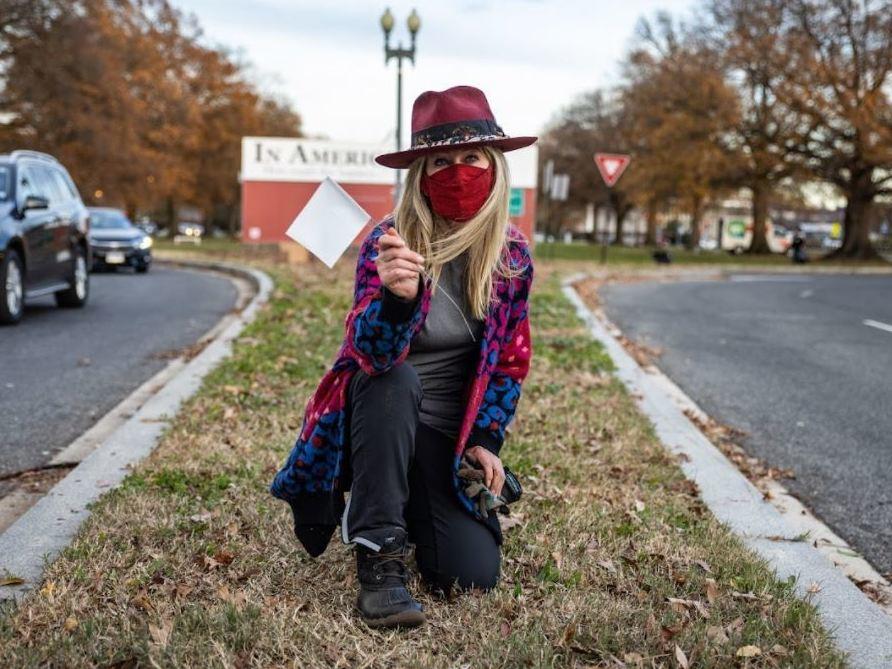 Artist Suzanne Brennan Firstenberg poses with one of the white flags installed near D.C.'s RFK Stadium in fall 2020. This month, thousands more are  featured in her latest exhibit on the National Mall.