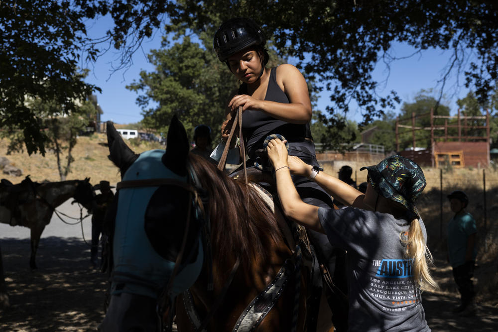 Sophia, a counselor-in-training from Denver, Colorado, goes horseback riding with assistance from a staff member of the horse ranch.