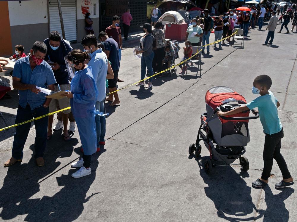 Asylum-seekers camping at El Chaparral crossing port line up to be vaccinated against COVID-19 last month in Tijuana, Mexico, on the border with the U.S.