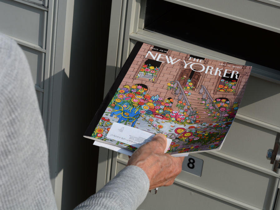 A woman retrieves a copy of <em>The New Yorker</em> magazine from her mailbox in Santa Fe, N.M., in 2020.