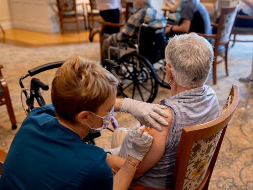 A health care worker administers a third dose of the Pfizer-BioNTech COVID-19 vaccine at a senior living facility in Worcester, Pa., in August.
