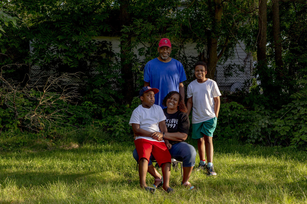 Jeneyah McDonald, her husband Earl and their children Josiah, 8, and Justice, 12, sit together in their yard outside of their home.
