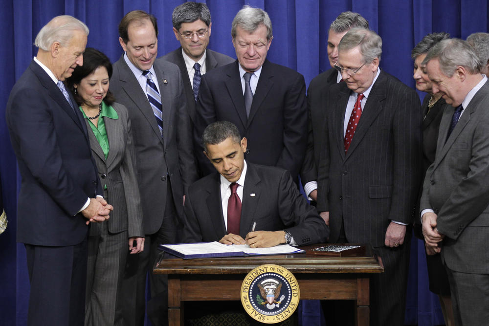 Then-President Barack Obama, joined by Republican and Democratic lawmakers, signs a bipartisan tax package that extends tax cuts for families at all income levels in December 2010.