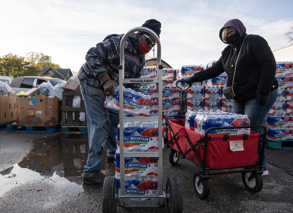 Volunteers help distribute cases of water bottles at Asbury United Methodist Help Center in Flint on Oct. 20, 2020. Authorities say Flint's water now meets federal safety guidelines, but many residents remain unconvinced.