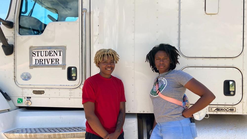 Amalya Livingston, right, poses in front of a truck at the DSC Training Academy on June 29, along with another student. Livingston says she faces sexism on the road but it doesn't deter her from driving.