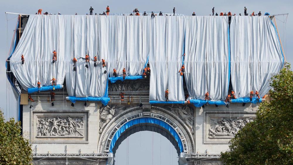 Workers unravel a silvery blue fabric during the wrapping of the L'Arc de Triomphe in Paris, in a posthumous installation by the artists Christo and Jeanne-Claude. The couple had dreamed of the project for decades.