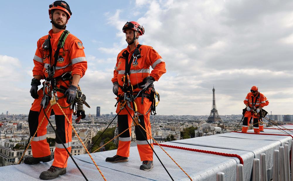 Rope access technicians look on during the inauguration of the Arc de Triomphe art installation in Paris, as the monument was wrapped in fabric as it was designed by the late artist Christo.