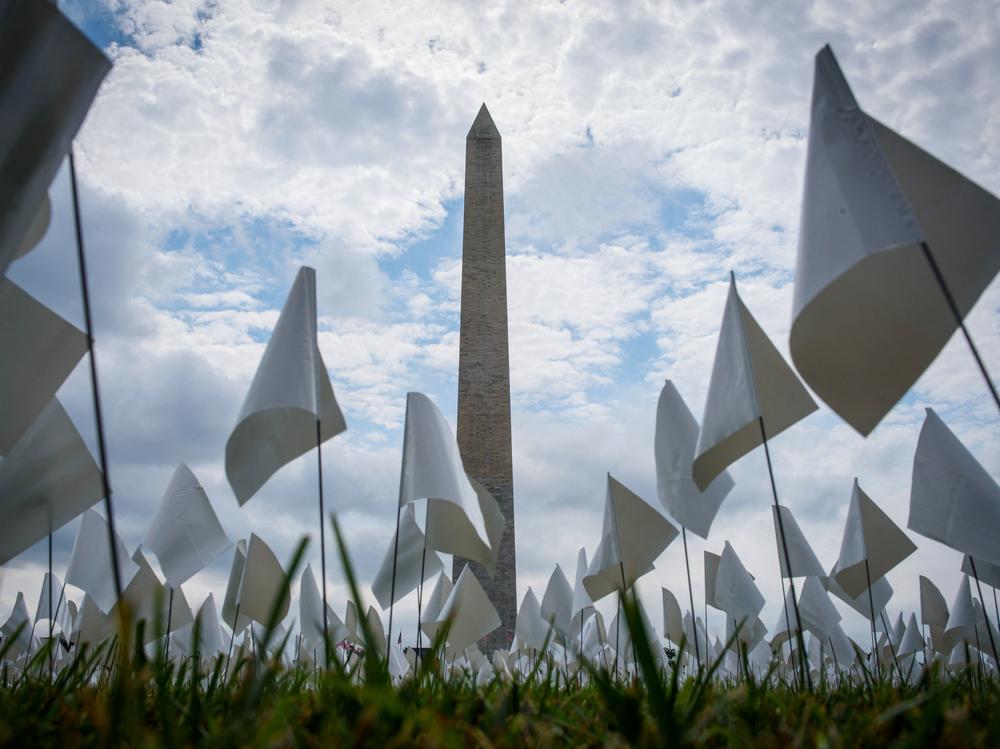 White flags stand near the Washington Monument on Tuesday during installation of a temporary art exhibit on the National Mall. More than 630,000 flags are part of artist Suzanne Brennan Firstenberg's <em>In America: Remember</em>, honoring Americans who have died of COVID-19.
